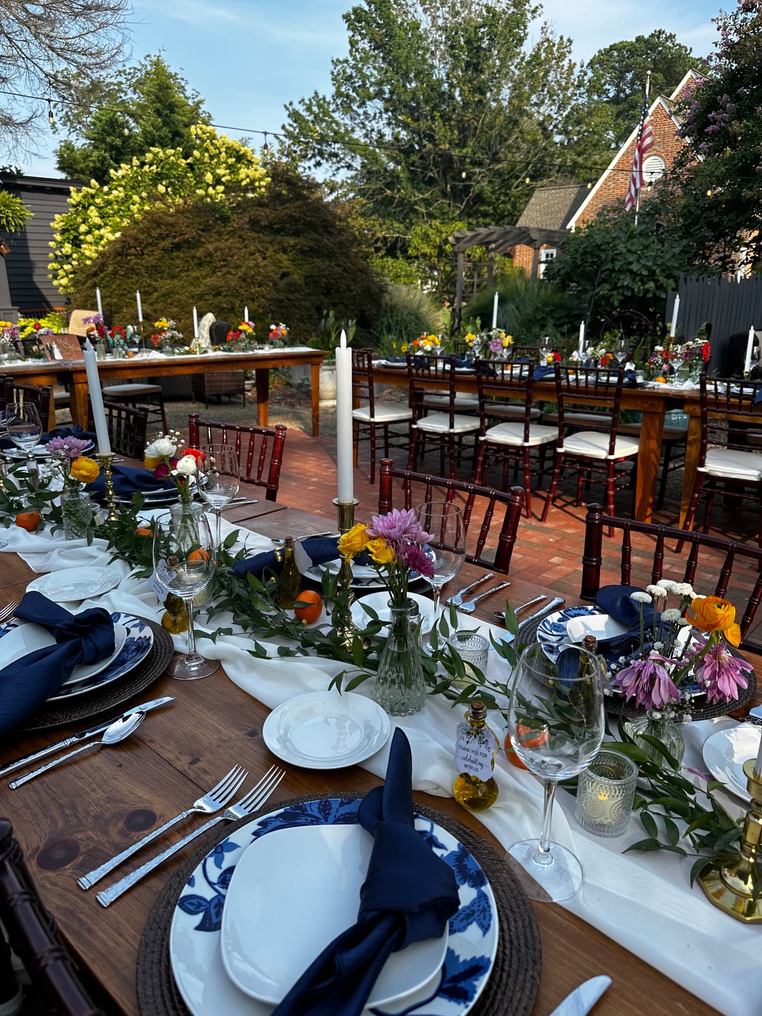 A beautifully arranged outdoor dining setup with floral centerpieces and elegant table settings.