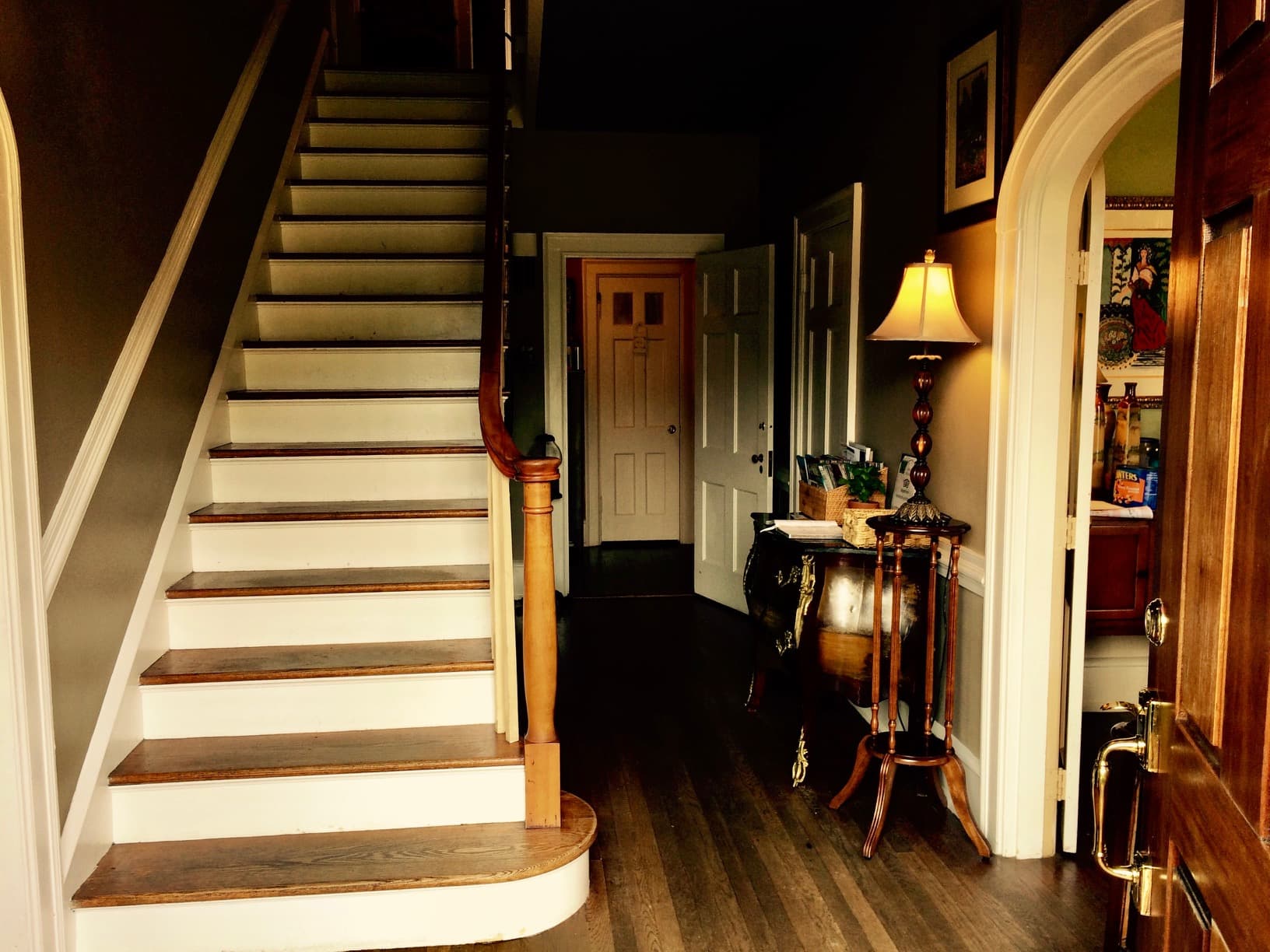 A warmly lit entryway features a staircase leading to an upper floor, with doors opening to other rooms.
