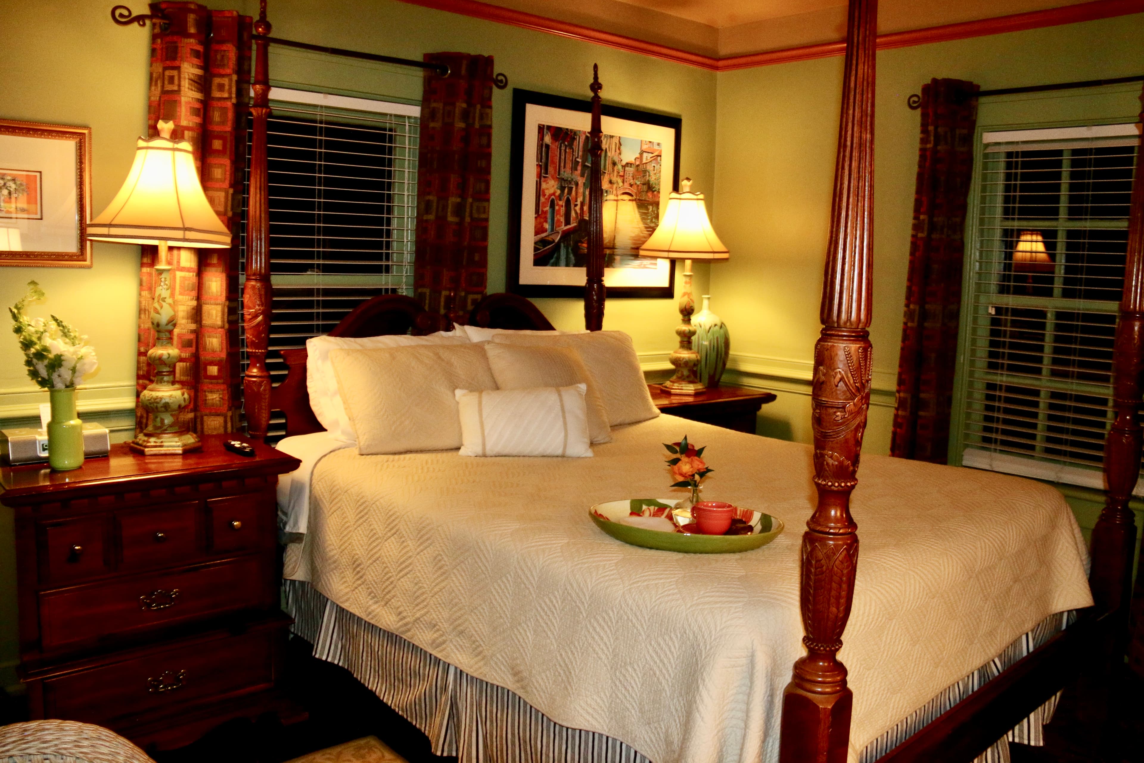 A cozy bedroom featuring a four-poster bed, warm lighting, and decorative accents.