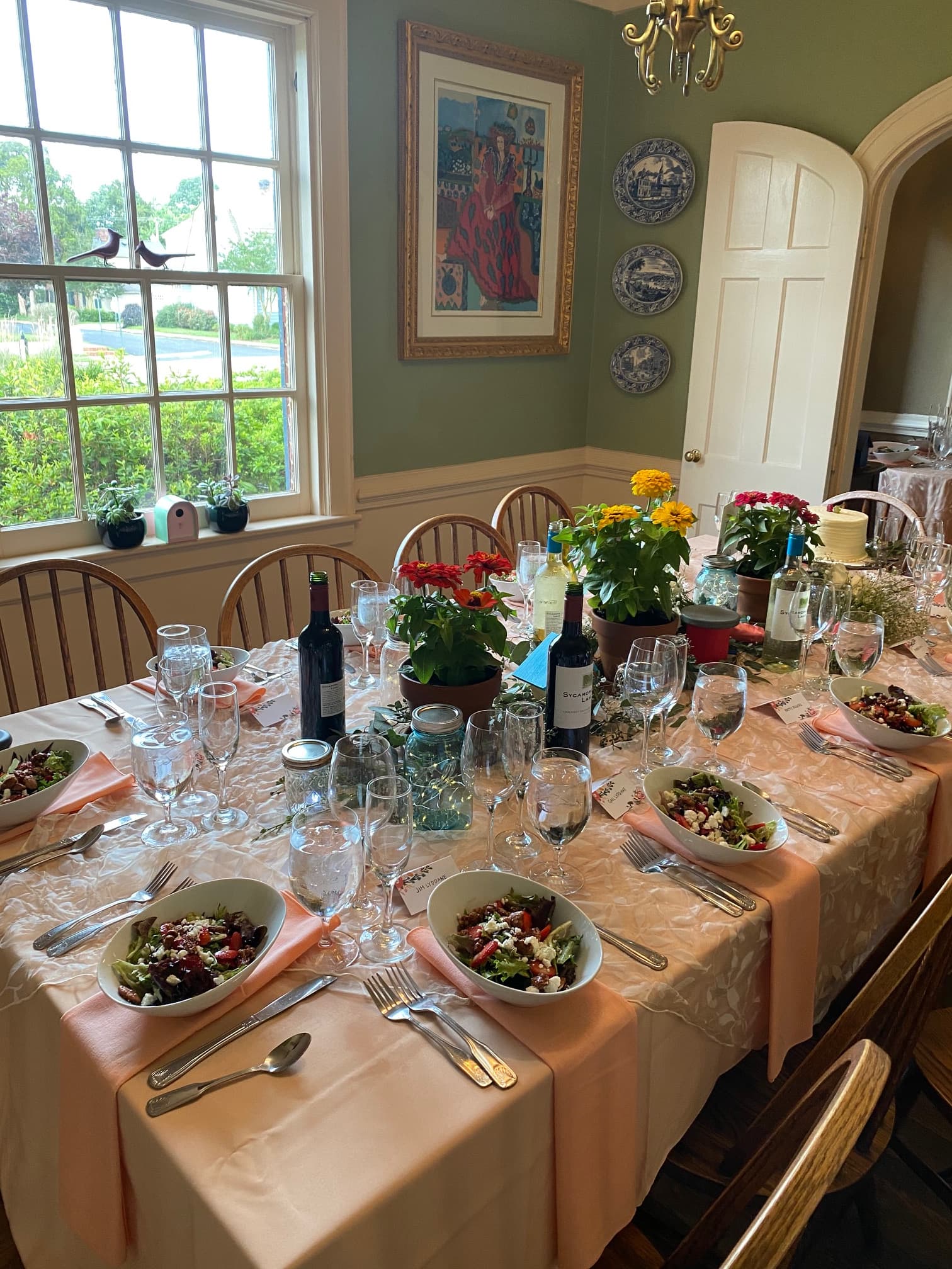 A beautifully set dining table with salads, wine bottles, and floral centerpieces.