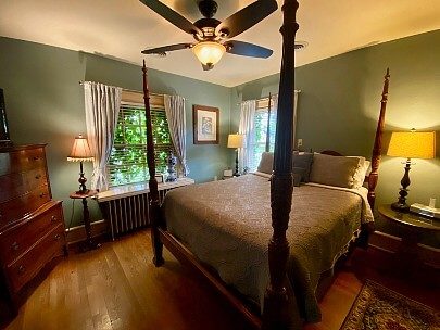 Guest room featuring green walls, four poster bed, two windows and brown accent furniture