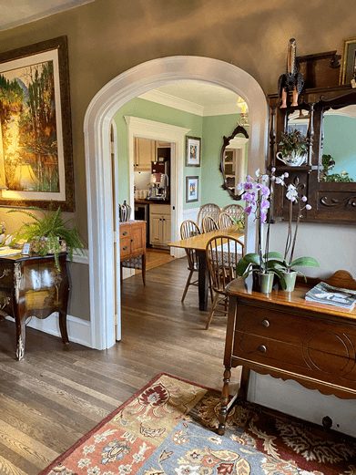 Beautiful arched doorway in a home with a view of an entryway and dining room with large table and doorway into a kitchen