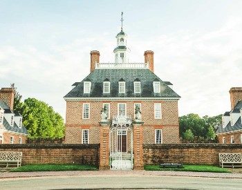 Stately historic brick home with numerous tall windows and brick gate flanking the front