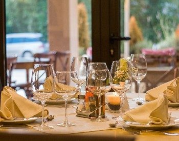 Table in a fine dining restaurant with white linens, white dishes and clear wine glasses