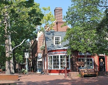 Street corner with cobblestone sidewalk and storefront of a red and grey building