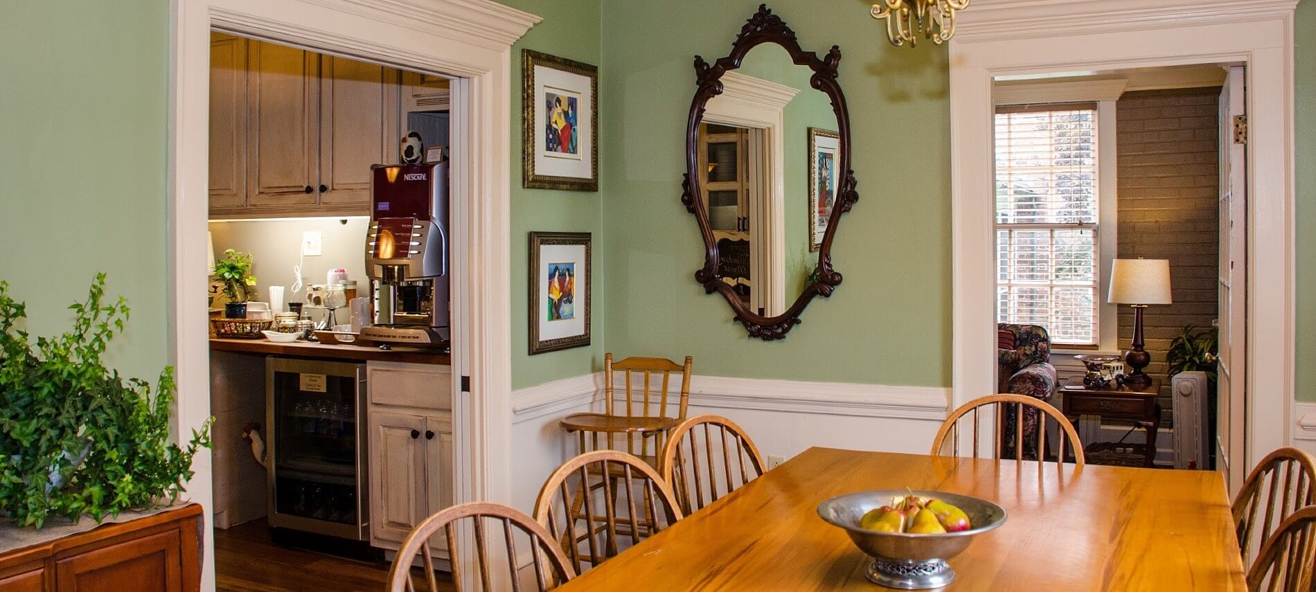 Dining room with large brown table and chairs and two open doorways into a kitchen and sitting room